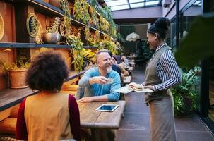 mensen zittend in restaurant, terwijl serveerster is portie voedsel foto