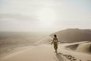 Namibië, namib, terug visie van vrouw wandelen blootsvoets Aan woestijn duin foto