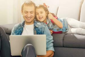 gebaard Mens en weinig meisje Bij huis familie tijd zittend Aan verdieping Aan tapijt browsen laptop samen glimlachen blij foto