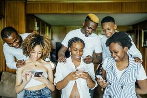 familie en vrienden gebruik makend van cel telefoons Bij huis foto