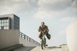 lachend zakenman rijden naar beneden een oprit Aan zijn fiets foto