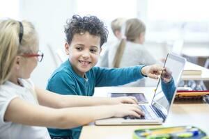 schooljongen en schoolmeisje gebruik makend van laptop samen in klasse foto
