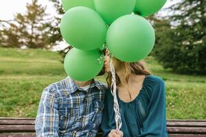 jong paar zoenen achter groen ballonnen foto