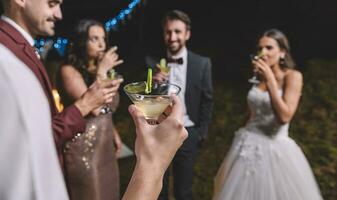 gelukkig vrienden drinken cocktails Aan een nacht veld- bruiloft partij foto