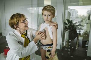 dokter onderzoeken kleuter jongen met een stethoscoop foto