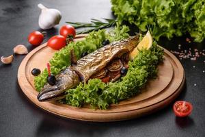 gebakken makreel met groenten op een houten bord met citroen foto
