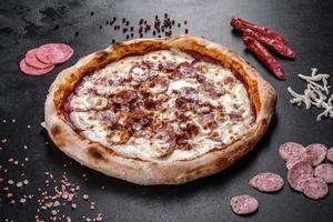 verse heerlijke Italiaanse pizza met vier soorten vlees op een donkere betonnen ondergrond concrete