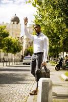 jonge Afro-Amerikaanse zakenman waitng een taxi in een straat foto