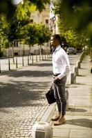 jonge Afro-Amerikaanse zakenman waitng een taxi in een straat foto