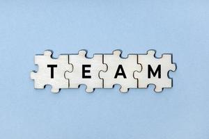 team woord over houten puzzelstukjes geïsoleerd op blauwe achtergrond. bovenaanzicht foto