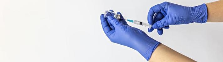 een medisch werker in medische handschoenen trekt een dosis coronavirusvaccin in een spuit. het concept van vaccinatie, immunisatie, preventie van mensen van covid-19 foto