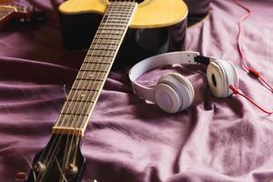 koptelefoon en klassieke gitaar in bed foto