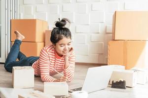 Aziatische vrouw bedrijfseigenaar die thuis werkt met verpakkingsdoos op de werkplek - online winkelen mkb-ondernemer of freelance werkconcept