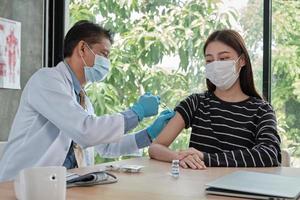 mannelijke arts die aziatische vrouw vaccineert om covid19 te beschermen. foto