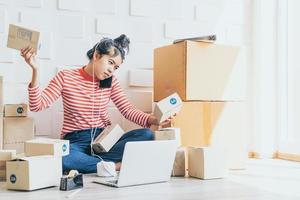 Aziatische vrouw bedrijfseigenaar die thuis werkt met verpakkingsdoos op de werkplek - online winkelen mkb-ondernemer of freelance werkconcept
