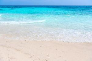 heldere zeegolven en wit zandstrand in de zomer. foto