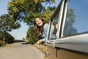 mooi vrouw Aan een weg reis met haar kampeerder, op zoek uit van auto venster foto