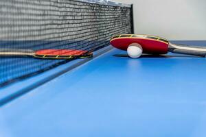 rood tafel tennis peddelen wit bal en een netto foto