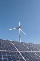 zonne- panelen en wind turbine tegen blauw lucht foto