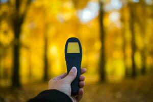 persoon controle temperatuur met thermometer tegen backdrop van herfst bladeren foto