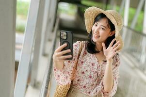 jong Aziatisch vrouw reiziger met het weven mand selfie met mobiel telefoon en staand Aan viaduct. reis reis levensstijl, wereld reizen ontdekkingsreiziger of Azië zomer toerisme concept. foto