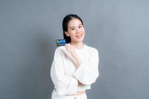 portret van een mooie jonge Aziatische vrouw in trui met creditcard met kopieerruimte foto
