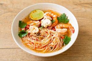 noedels met pittige soep en garnalen in witte kom - tom yum kung - Aziatisch eten foto