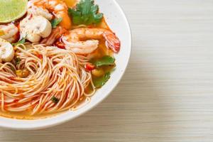 noedels met pittige soep en garnalen in witte kom - tom yum kung - Aziatisch eten foto