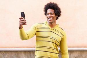 zwarte man met afrohaar en koptelefoon met smartphone.
