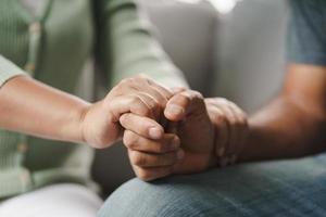 vriend of familie zitten en houden elkaars hand opvrolijken voor een mentale depressieve man foto