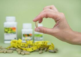 een vrouwen hand- is Holding een groen pil. sport- vitamines en supplementen. detailopname. selectief focus. foto