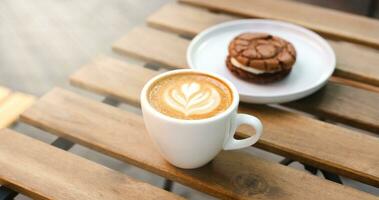 een kop van aromatisch cappuccino en heerlijk chocola koekjes Aan een tafel in een straat cafe. koffie breken Aan een zomer zonnig dag. detailopname. kopiëren ruimte. foto