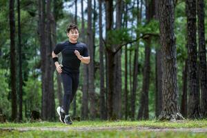 Aziatisch spoor loper is rennen buitenshuis in de pijnboom Woud aarde weg voor oefening en training activiteiten opleiding naar ras in altra marathon naar bereiken gezond levensstijl en geschiktheid concept foto