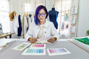 modieus freelance naaister is ontwerpen Aan nieuw jurk door tekening illustrator gebruik makend van kleur swatch terwijl werken in artistiek werkplaats studio voor mode ontwerp en kleding bedrijf industrie foto