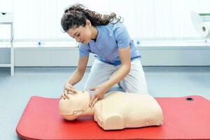 vrouw beoefenen cpr techniek Aan dummy gedurende eerste steun opleiding. eerste steun opleiding - cardiopulmonaal reanimatie. eerste steun Cursus Aan cpr pop. foto