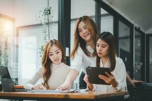 drie Dames analyseren documenten terwijl zittend Aan een tafel in kantoor. vrouw leidinggevenden Bij werk in kantoor bespreken sommige papierwerk. foto