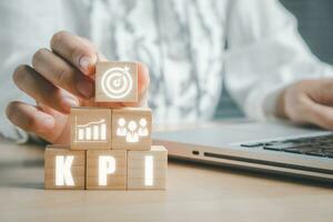 kpi sleutel prestatie indicator bedrijf en industrieel analyse concept, persoon hand- Holding houten blok met kpi icoon Aan virtueel scherm. foto