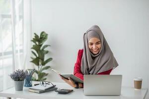 portret van mooi moslim zakenvrouw glimlachen Bij de camera, zittend Bij haar bureau. foto