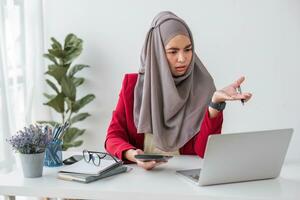echt jong vrouw vervelend hijab zittend Bij bureau werken Aan nieuw bedrijf project alleen in modern kantoor foto