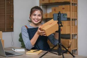 Aziatisch blogger recensie producten en video camera Aan haar telefoon, verkopen hen online, en vitrine haar producten online Aan sociaal media. ecommerce bedrijf leven streaming vlog nieuw normaal concept foto