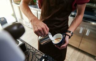 detailopname van professioneel barista gieten gestoomd melk in koffie kop maken latte achter bar teller foto