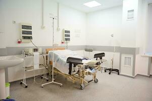 leeg levering kamer met bed en medisch uitrusting in moederschap afdeling Bij ziekenhuis. bevalling. levering. arbeid concept foto