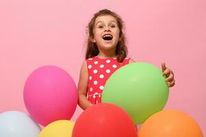 prachtig verjaardag baby meisje, 4 jaren kind knuffelen kleurrijk ballonnen, vreugde op zoek omhoog, geïsoleerd over- roze achtergrond met kopiëren ruimte. verjaardag evenement concept, kinderen bescherming, gelukkig vrouw dag foto