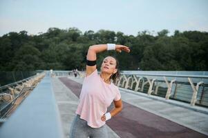 mooi geschiktheid jong vrouw oefenen buitenshuis Aan de brug, uitrekken haar lichaam voordat ochtend- routine- joggen Bij zonsopkomst. sport, conditie,motivatie, gezond levensstijl en gewicht verlies concept foto