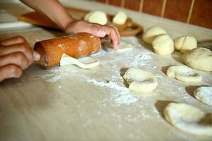 focus Aan vrouw handen rollend de deeg met een rollend pin Aan de keuken teller naar maken ronde knoedel mallen. detailopname, voedsel achtergrond. werkwijze van Koken knoedels stap door stap foto