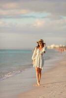 jong gelukkig vrouw Aan de strand genieten haar zomer vakantie Bij zonsondergang foto