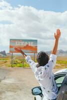 mooi vrouw Aan haar reis door de auto. Welkom naar Utah weg teken. groot Welkom teken groeten reist in monument vallei, Utah foto