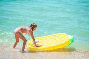 weinig gelukkig meisje met opblaasbaar lucht matras in de zee hebben pret foto