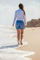 jong gelukkig vrouw wandelen Aan de strand foto