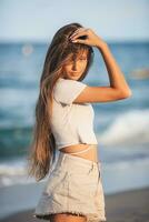 aanbiddelijk jong meisje met mooi lang haar- genieten tropisch strand vakantie. de meisje Aan de kust Bij zonsondergang foto